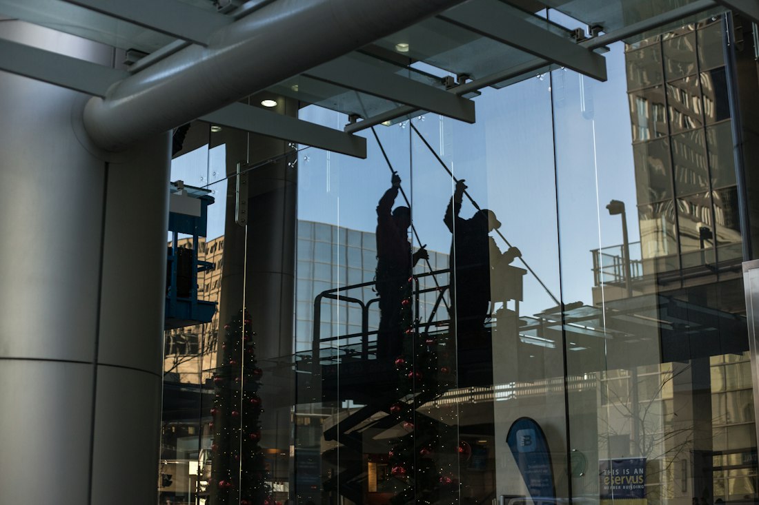 Crew cleaning a glass building facade from an access platform